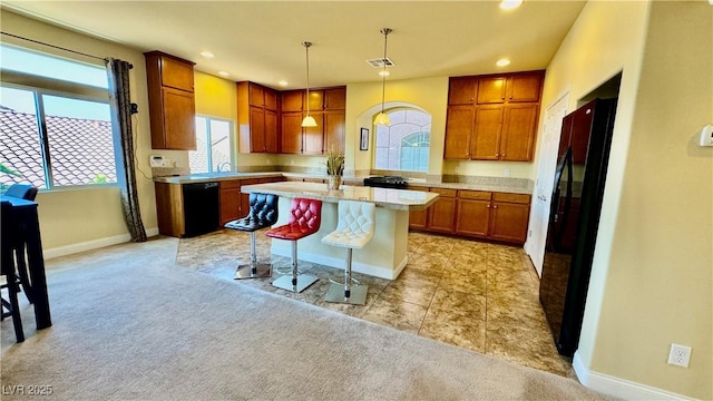 kitchen featuring a breakfast bar area, a center island, pendant lighting, light colored carpet, and black appliances