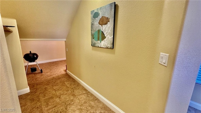 hallway with lofted ceiling and a textured ceiling