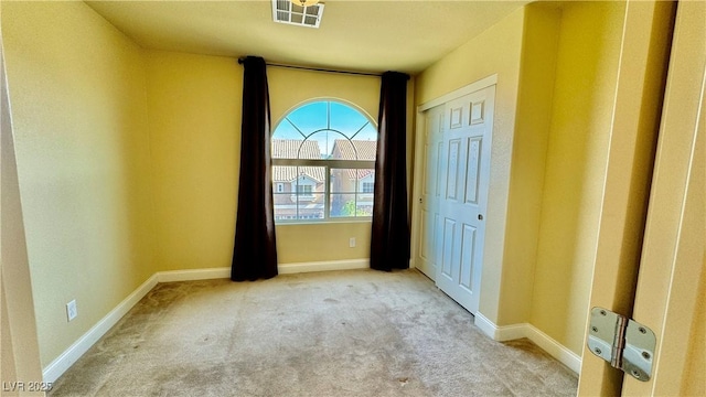 unfurnished bedroom featuring light carpet and a closet