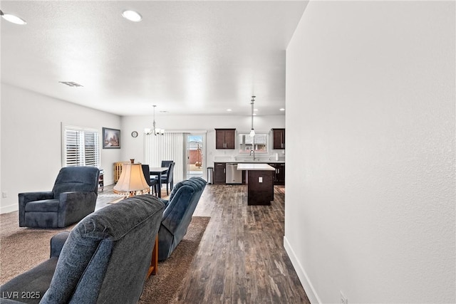 living room with an inviting chandelier, dark hardwood / wood-style floors, and sink