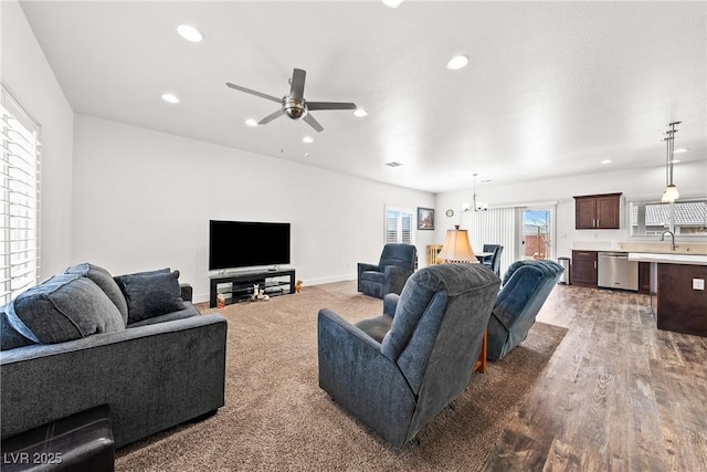 living room with hardwood / wood-style flooring, sink, and ceiling fan with notable chandelier