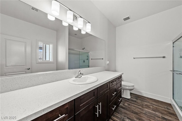 bathroom featuring vanity, toilet, an enclosed shower, and hardwood / wood-style floors