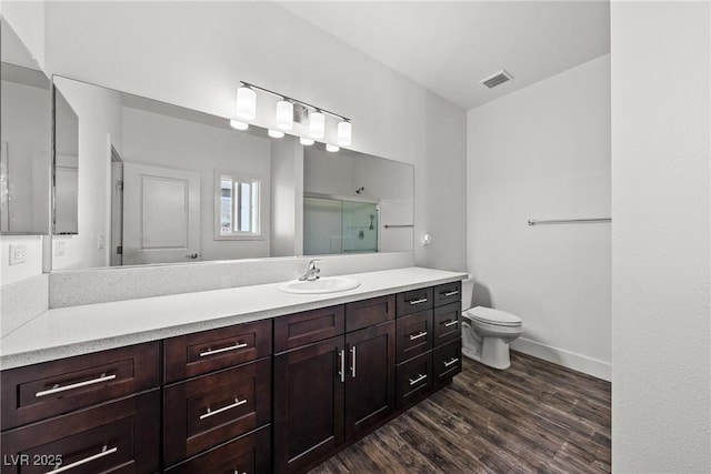 bathroom with hardwood / wood-style flooring, vanity, toilet, and a shower with door