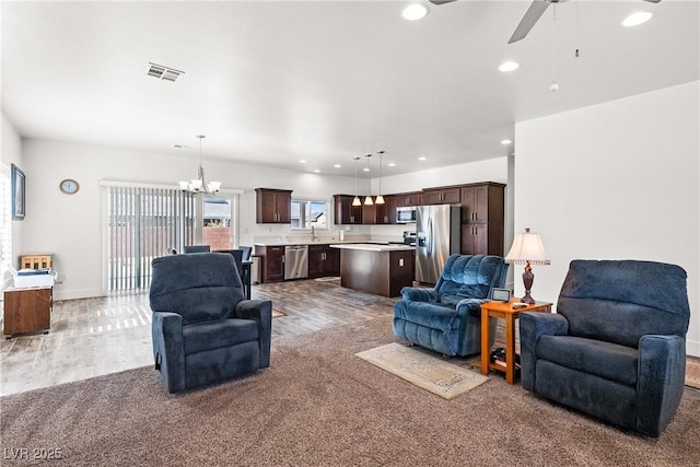 living room featuring ceiling fan with notable chandelier and hardwood / wood-style floors