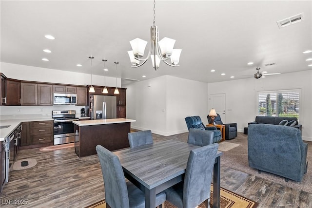 dining space with dark hardwood / wood-style floors and ceiling fan with notable chandelier