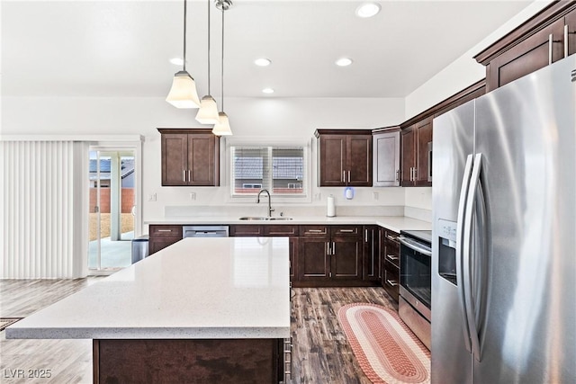 kitchen featuring sink, appliances with stainless steel finishes, dark brown cabinets, a center island, and decorative light fixtures