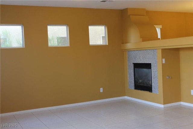 unfurnished living room with light tile patterned floors and a tile fireplace