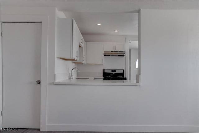 kitchen featuring stove, sink, and white cabinets