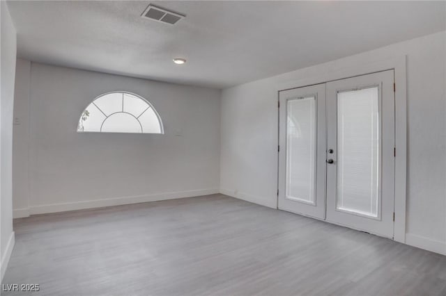 empty room featuring french doors and light hardwood / wood-style floors