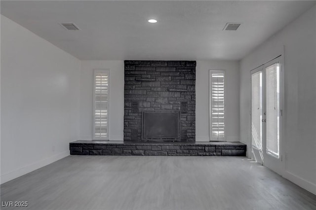 unfurnished living room with a stone fireplace and light wood-type flooring