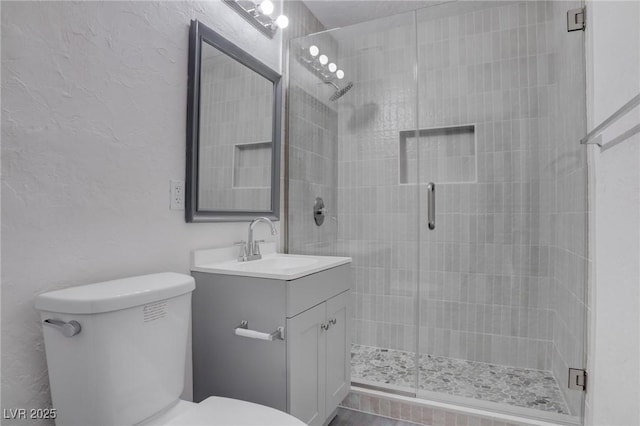 bathroom with a shower with door, vanity, and toilet