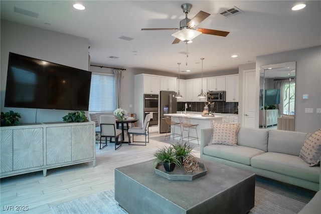 living room featuring ceiling fan and light hardwood / wood-style flooring