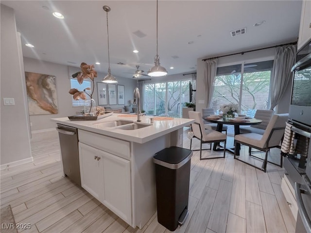 kitchen featuring sink, pendant lighting, dishwasher, white cabinets, and a kitchen island with sink