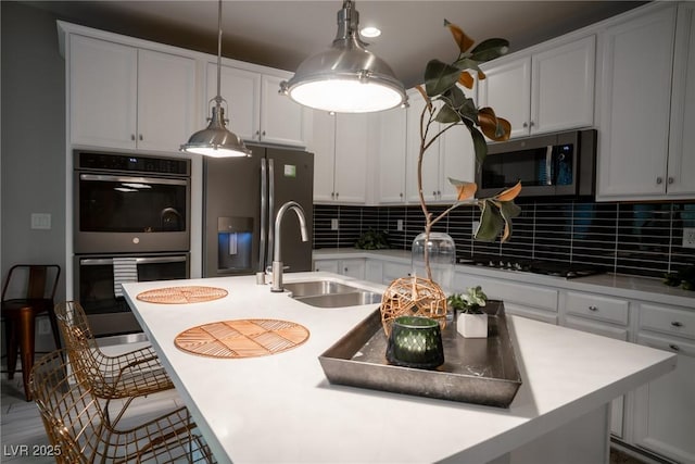 kitchen featuring a kitchen bar, appliances with stainless steel finishes, sink, a kitchen island with sink, and decorative backsplash