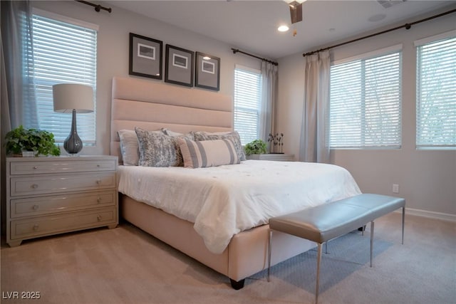 bedroom featuring multiple windows, ceiling fan, and light colored carpet