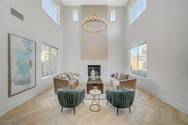 living area featuring parquet flooring, a healthy amount of sunlight, and a notable chandelier