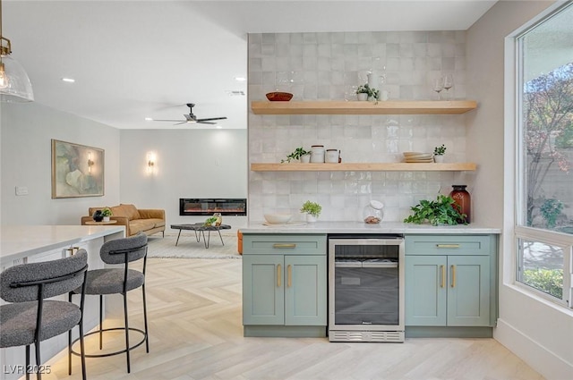 bar with tasteful backsplash, ceiling fan, beverage cooler, and light parquet flooring