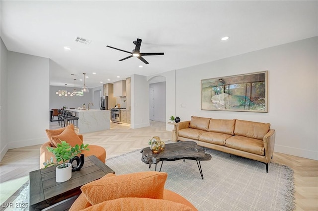 living room with light parquet flooring, sink, and ceiling fan with notable chandelier