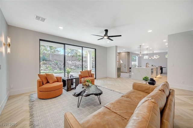 living room featuring ceiling fan, light parquet flooring, and sink