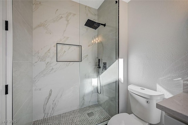 bathroom featuring vanity, tiled shower, and toilet