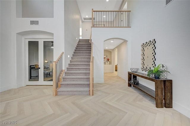 foyer entrance with french doors, parquet flooring, and a high ceiling