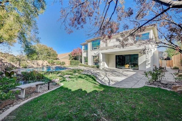 rear view of property with a yard, a patio area, and a balcony