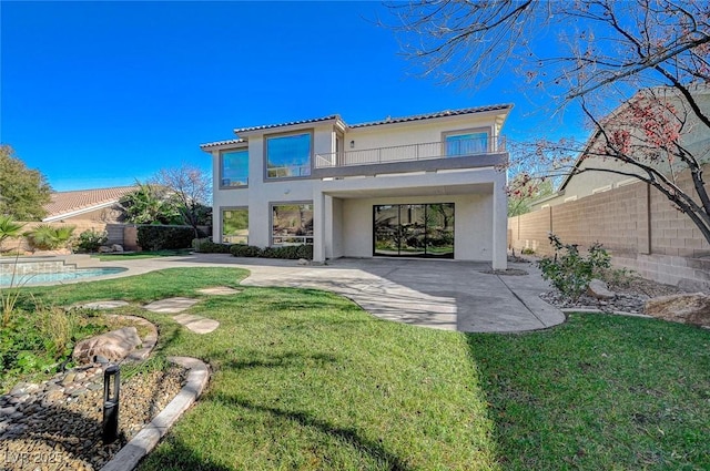 rear view of property featuring a balcony, a yard, a fenced in pool, and a patio