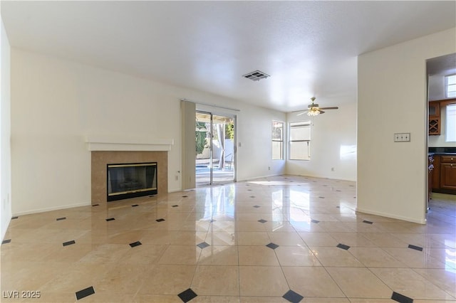 unfurnished living room with ceiling fan, a fireplace, and light tile patterned floors