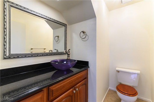 bathroom with vanity, lofted ceiling, tile patterned floors, and toilet