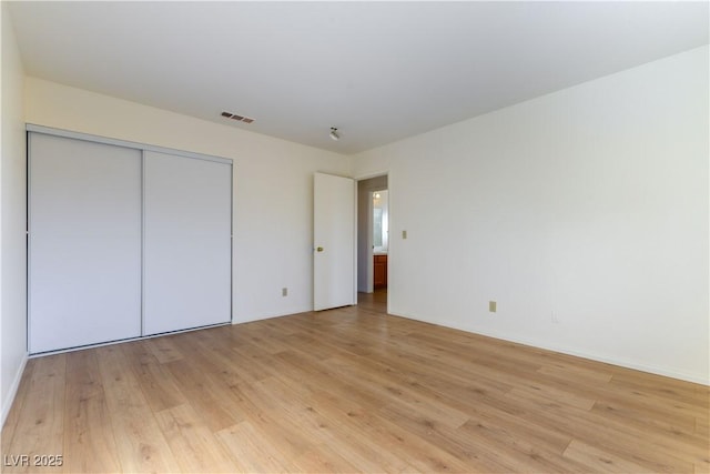 unfurnished bedroom with a closet and light wood-type flooring