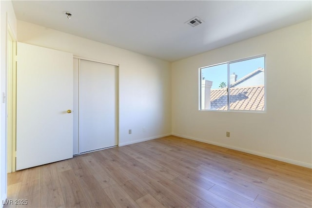 unfurnished bedroom featuring light hardwood / wood-style flooring and a closet