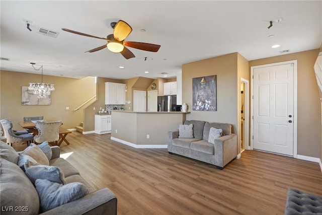 living room featuring wood-type flooring, radiator, and ceiling fan with notable chandelier