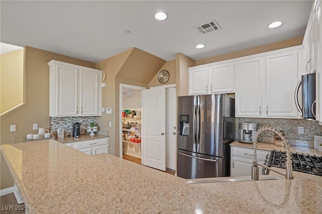 kitchen featuring sink, appliances with stainless steel finishes, light stone countertops, white cabinets, and decorative backsplash