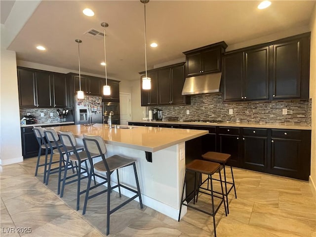 kitchen with appliances with stainless steel finishes, a breakfast bar, decorative light fixtures, sink, and a kitchen island with sink