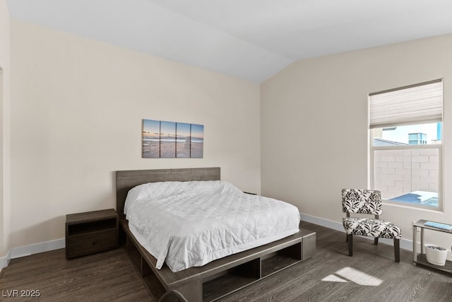 bedroom with vaulted ceiling, dark wood finished floors, and baseboards