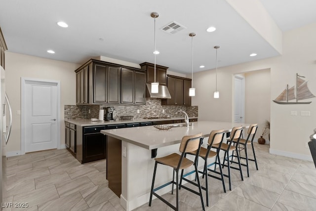 kitchen with light countertops, dark brown cabinetry, decorative light fixtures, and under cabinet range hood