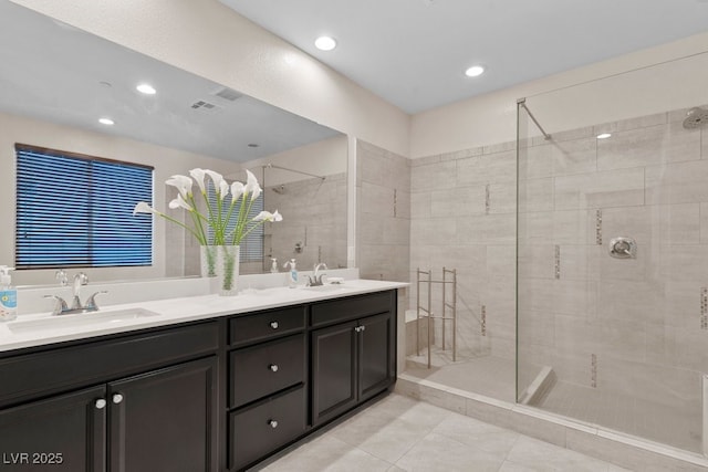 bathroom featuring double vanity, a walk in shower, a sink, and tile patterned floors