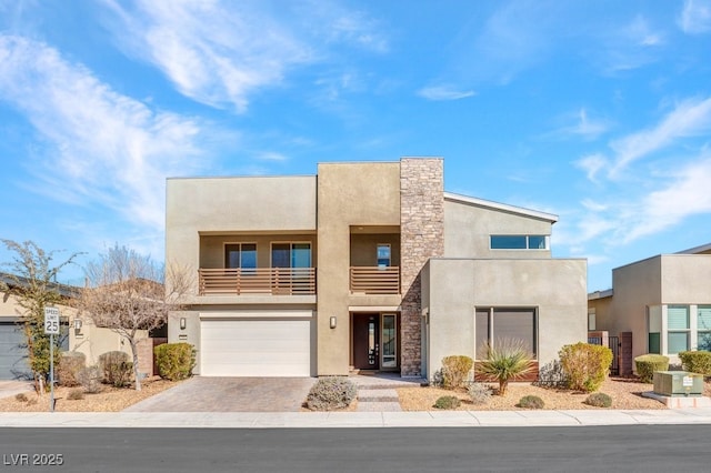 view of front of home featuring a garage, stone siding, driveway, and stucco siding