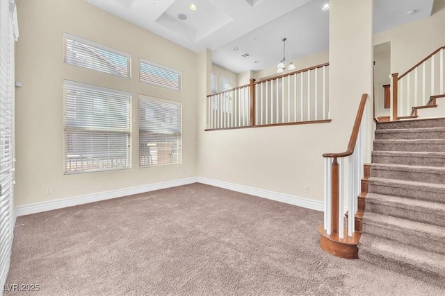 staircase featuring coffered ceiling, a high ceiling, and carpet flooring