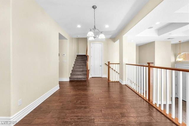 hall with a notable chandelier and dark hardwood / wood-style flooring