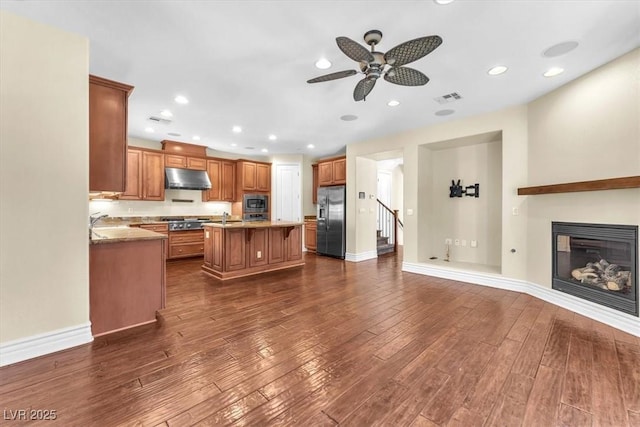 kitchen with appliances with stainless steel finishes, dark hardwood / wood-style floors, sink, a center island, and ceiling fan