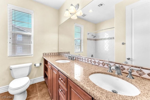 bathroom featuring vanity, tile patterned flooring, toilet, and tiled shower