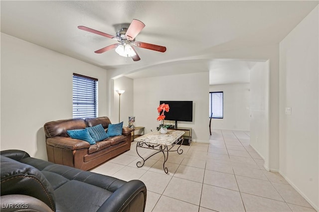 living area featuring ceiling fan, light tile patterned flooring, a wealth of natural light, and baseboards