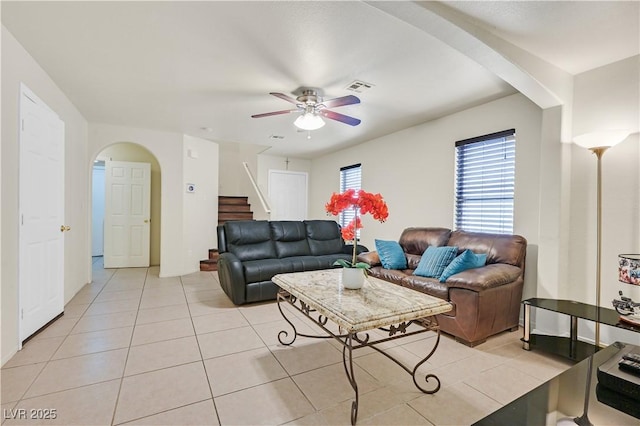 living room with arched walkways, visible vents, stairway, light tile patterned flooring, and ceiling fan