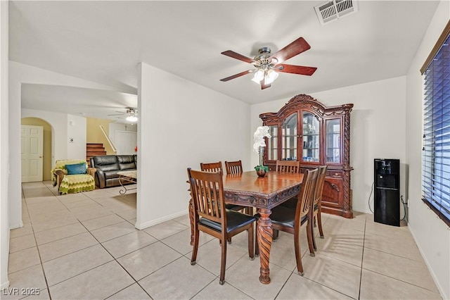 dining area with arched walkways, light tile patterned floors, visible vents, stairway, and a ceiling fan