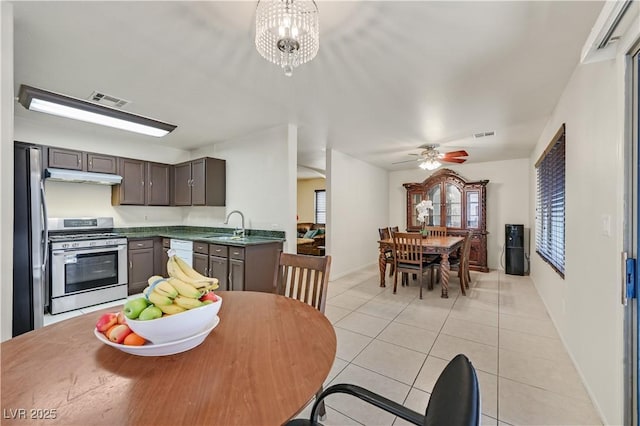 kitchen featuring dark countertops, visible vents, appliances with stainless steel finishes, light tile patterned flooring, and a sink