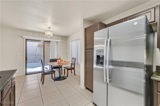 kitchen featuring light tile patterned floors, dark stone counters, stainless steel refrigerator with ice dispenser, and baseboards