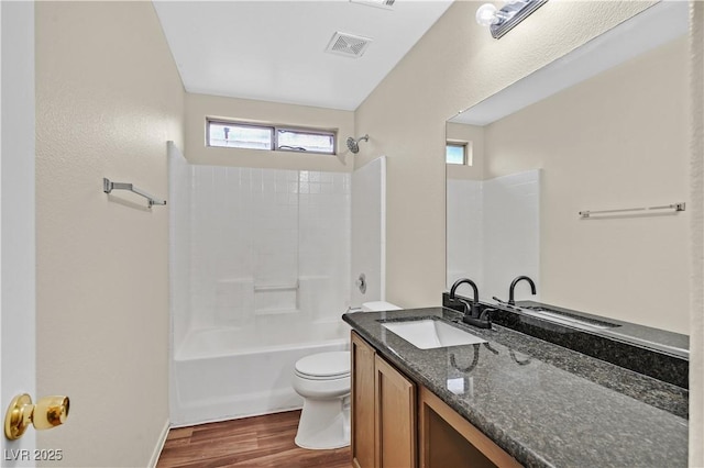 bathroom featuring visible vents, toilet, wood finished floors,  shower combination, and vanity