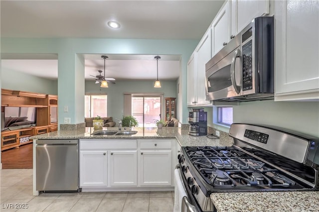 kitchen with appliances with stainless steel finishes, decorative light fixtures, white cabinetry, sink, and kitchen peninsula