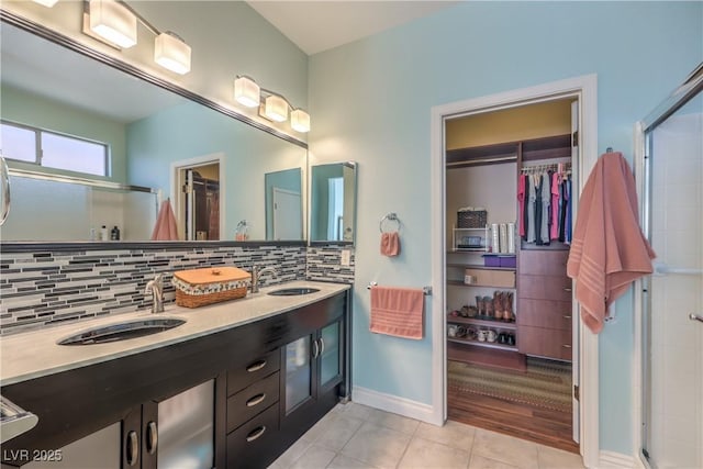 bathroom with tile patterned flooring, vanity, a shower with door, and backsplash